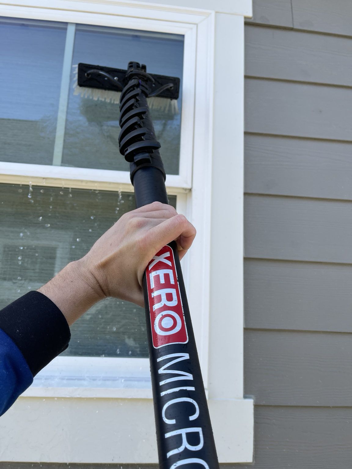 Water-fed brush cleaning exterior window glass at a Clayton, NC home