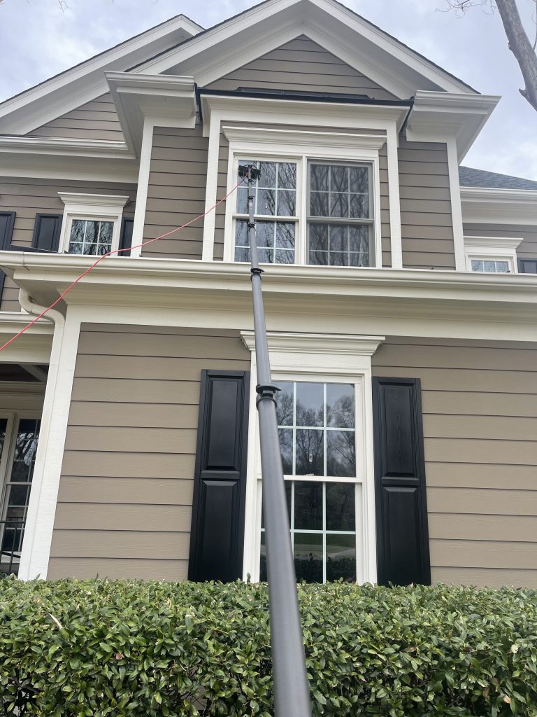 Water-fed pole cleaning upper-story windows on a home in Raleigh, NC